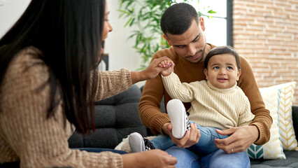 Fototapeta premium Couple and son hugging each other sitting on sofa at home