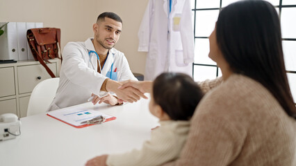 Fototapeta premium Couple and son smiling confident shake hands at clinic