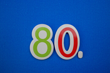 The number 80, placed on a blue background, photographed from above.