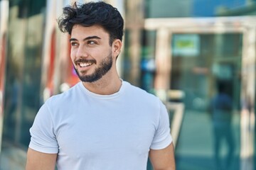 Young hispanic man smiling confident looking to the side at street