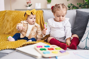 Adorable girls playing with maths puzzle game holding scissors at home