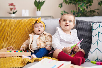 Adorable girls playing with abacus holding scissors at home