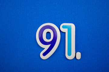 Placed on a blue background, photographed from above, the number 91.
