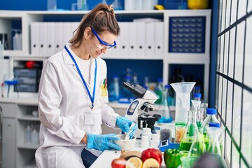 Young woman scientist smiling confident working at laboratory