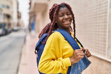 African american woman student smiling confident wearing backpack at street