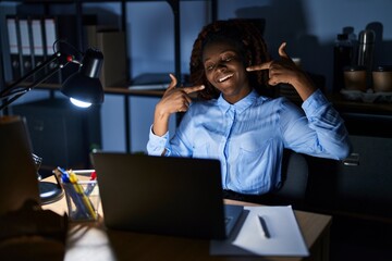 African woman working at the office at night smiling cheerful showing and pointing with fingers teeth and mouth. dental health concept.