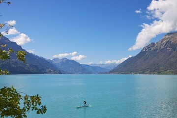 Scenic view of a person paddleboarding in the tranquil lake Breinz surrounded by mountains in summer