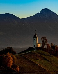 Vertical shot of The Church of St. Primoz and Felicijan on an evergreen hill in Jamnik, Slovenia