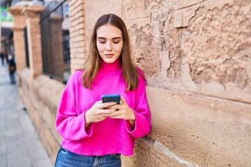 Young woman smiling confident talking on the smartphone at street