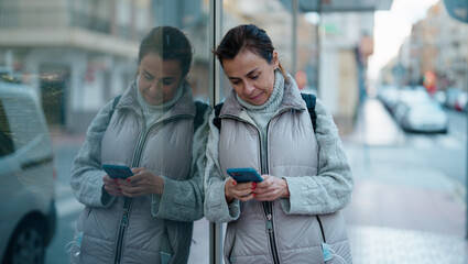 Obraz premium Middle age hispanic woman smiling confident using smartphone at street
