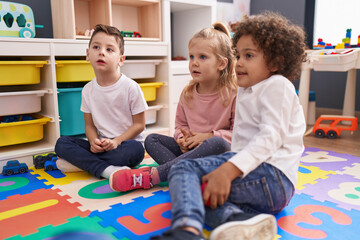 Group of kids sitting on floor with relaxed expression at kindergarten