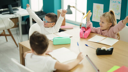 Obraz premium Group of kids students sitting on table with winner expression at classroom