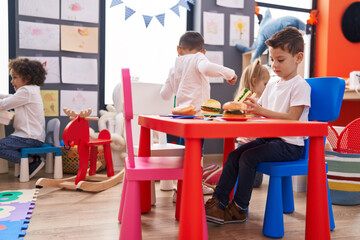 Group of kids playing with play food toy sitting on table at kindergarten