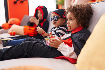Group of kids wearing halloween costume eating candies at home
