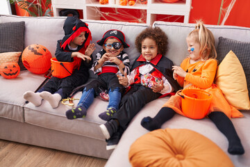 Group of kids wearing halloween costume eating candies at home