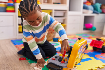 African american boy playing with toy sitting on floor at home