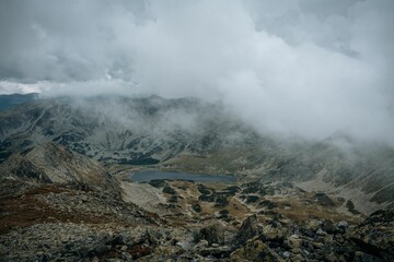Beautiful view of a rocky mountain landscape with small lake in the middle in fog