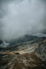 Vertical of a small lake surrounded by the big mountains on a cloudy day during the daytime