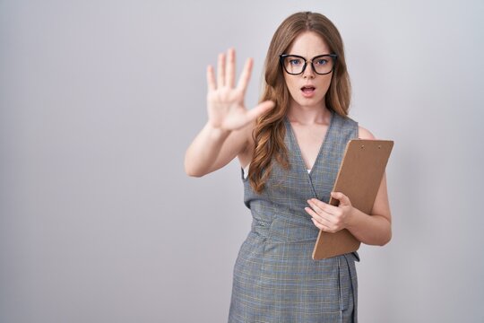 Caucasian woman wearing glasses and business clothes doing stop gesture with hands palms, angry and frustration expression