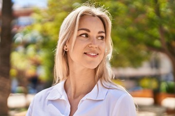 Young blonde woman smiling confident standing at park