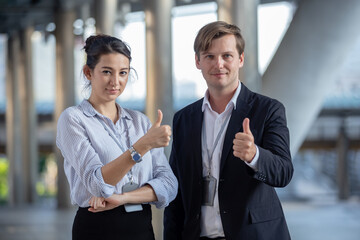 Portrait two businesspeople partners thumbs up looking at camera. businessman and businesswoman successful current project. partnership and connection business concept.