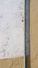 Tubería metálica en pared de estuco blanco y amarilla