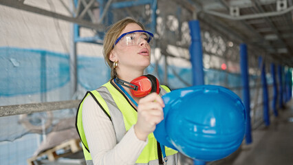 Young blonde woman architect taking hardhat out sweating at street