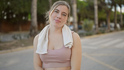 Young blonde woman smiling confident wearing sportswear at street