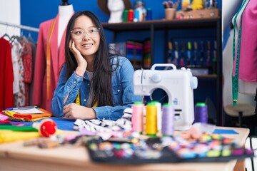 Fototapeta premium Young chinese woman tailor smiling confident using sewing machine at clothing factory
