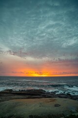 Scenic vertical view of ocean waves washing the rocky shore during a mesmerizing sunset in, Portugal