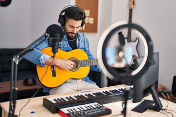 Young hispanic man musician having online guitar lesson at music studio