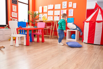 Adorable caucasian boy playing on back view at kindergarten