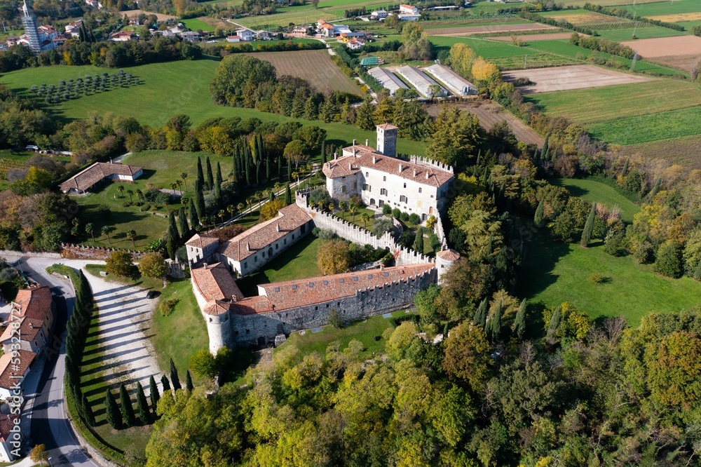 Wall mural aerial view of the castello villalta castle in italy, surrounded by a grass field on a sunny day