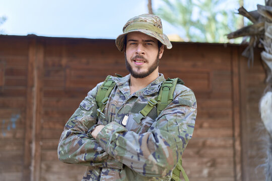 Young hispanic man wearing soldier uniform standing with arms crossed gesture at park