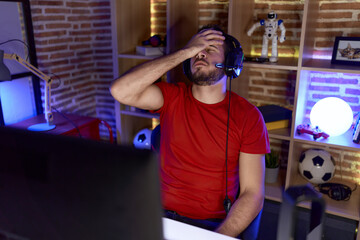 Young hispanic man streamer stressed using computer at gaming room