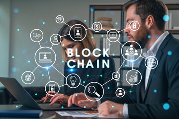 Thoughtful businesspeople typing on laptop at office workplace. Concept of team work, business education, internet surfing, brainstorm, project information technology. Blockchain hologram