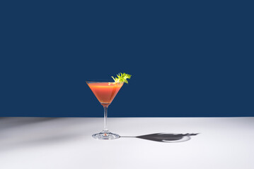 Coctel Bloody Mary decorado con hoja de apio sobre fondo azul	