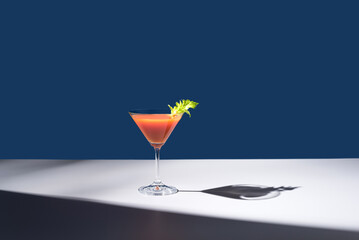 Coctel Bloody Mary decorado con hoja de apio sobre fondo azul	