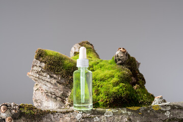 Botella de extracto de musgo, esencia con cuentagotas sobre un tronco de árbol con musgo	