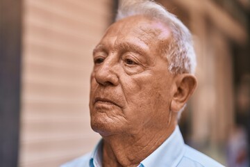 Senior grey-haired man with relaxed expression standing at street