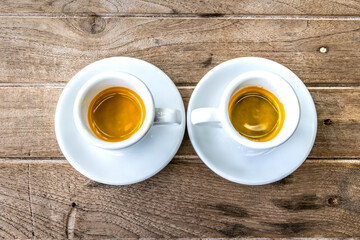 Two white cups of espresso on wooden background.