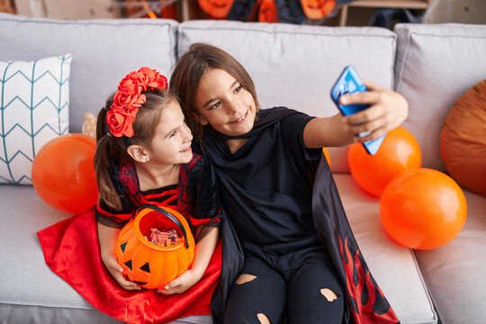 Adorable boy and girl wearing halloween costume make selfie by smartphone at home