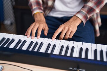 Fototapeta premium Young hispanic man musician playing piano at music studio