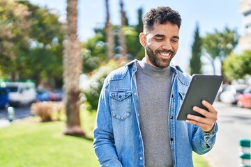 Fototapeta premium Young hispanic man smiling confident using touchpad at park