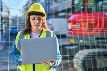 Young beautiful plus size woman architect using laptop at street