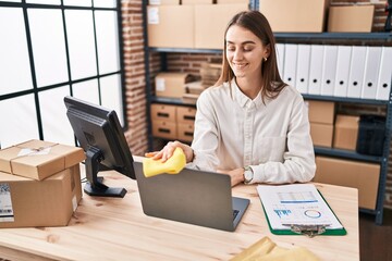 Young caucasian woman ecommerce business worker cleaning laptop at office