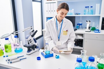 Young caucasian woman scientist weighing liquid reading notebook at laboratory