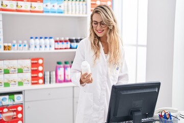 Young woman pharmacist holding pills bottle working at pharmacy