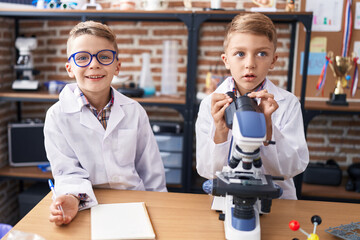 Adorable boys students using microscope writing notes at laboratory classroom