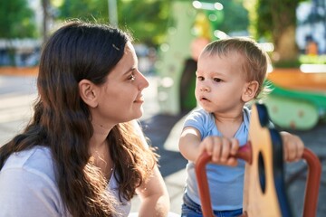 Mother and son playing on swing at park playground